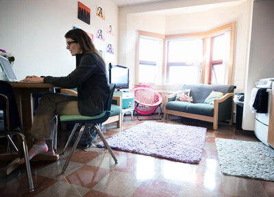 A student works at her laptop in the common room of her apartment in Crescent