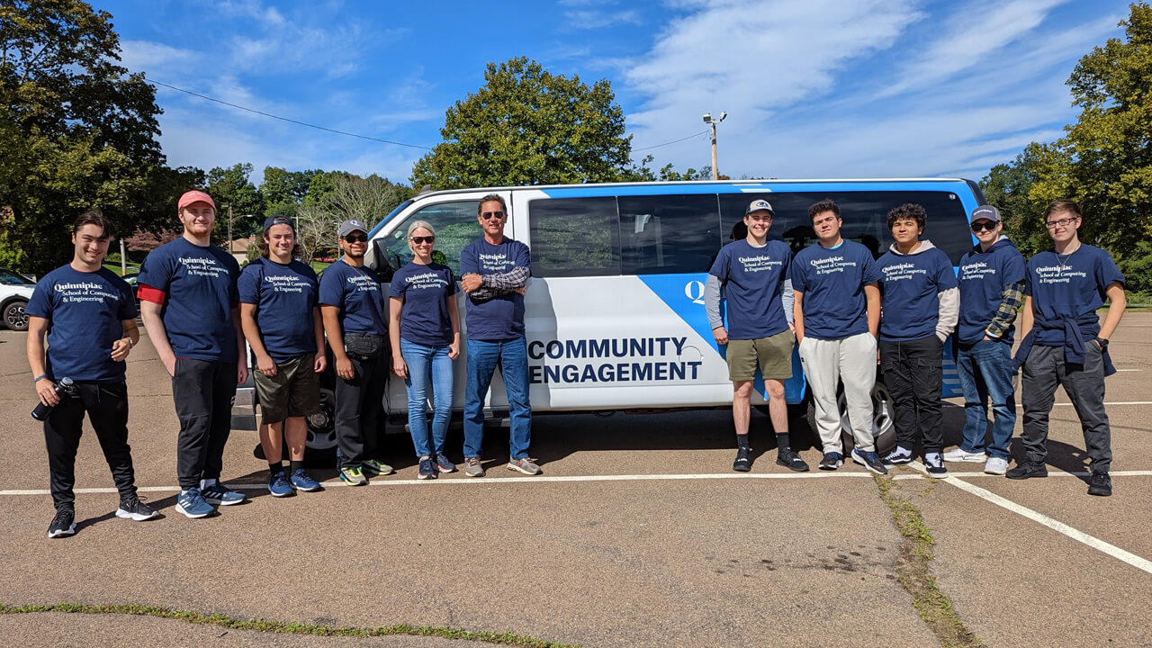 Students in the Medallions LLC take a group photo in front of a van.