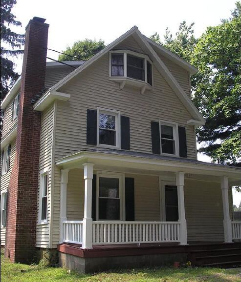 Tan house with front porch and brick chimney