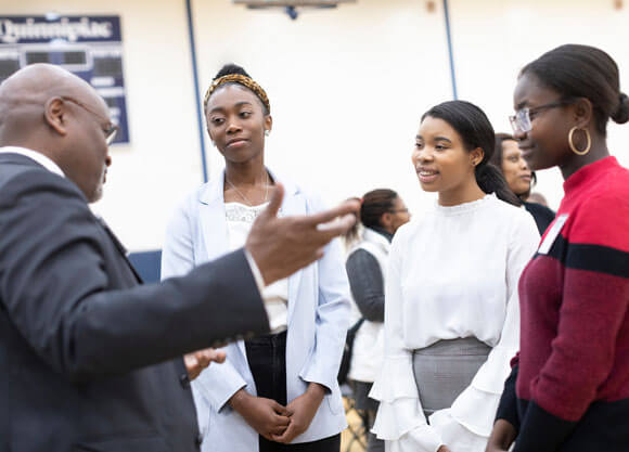 Three students speak with Richard A. Robinson during the Black History Month event.