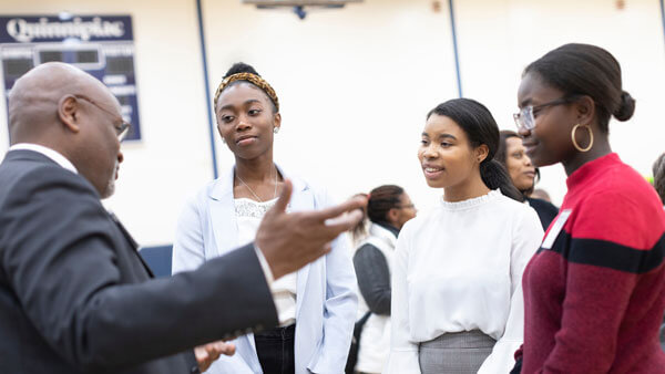 Three students speak with Richard A. Robinson during the Black History Month event.