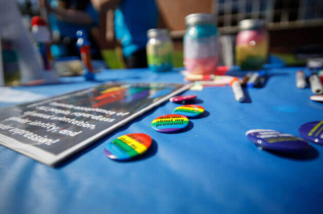 Buttons on a table that read, "Ask about my pronoun"