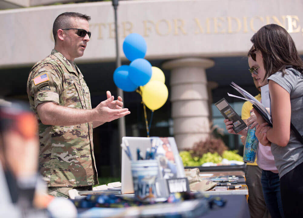 A veteran in military regalia speaks with two people outside