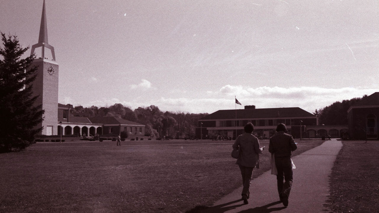 Two students walk across the Quinnipiac quad in 1977